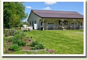 A large white barn with a lawn in front of it.