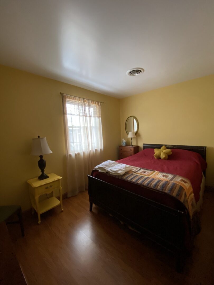 A bedroom with yellow walls and wooden floors.
