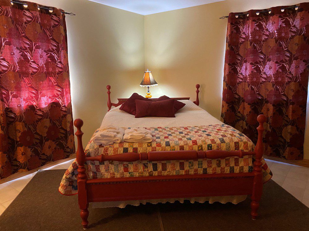 A bed room with a red wooden frame and two pillows